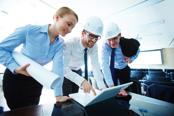 Young architects consulting at meeting and using laptop